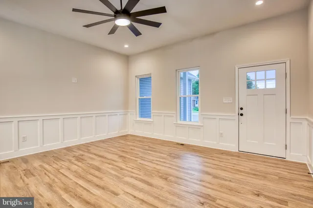 a view of an empty room with wooden floor and a window