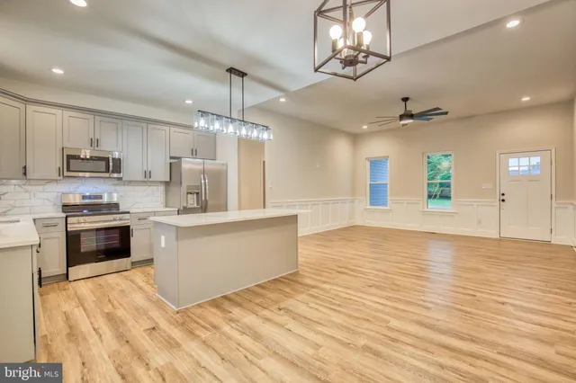 a large kitchen with cabinets wooden floor and stainless steel appliances