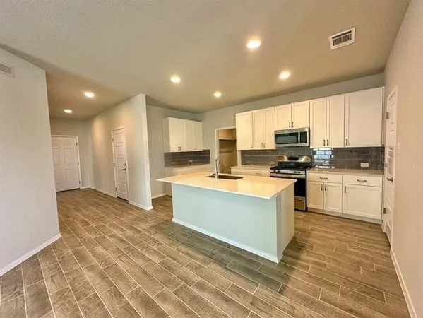 a kitchen with granite countertop a stove top oven and cabinets