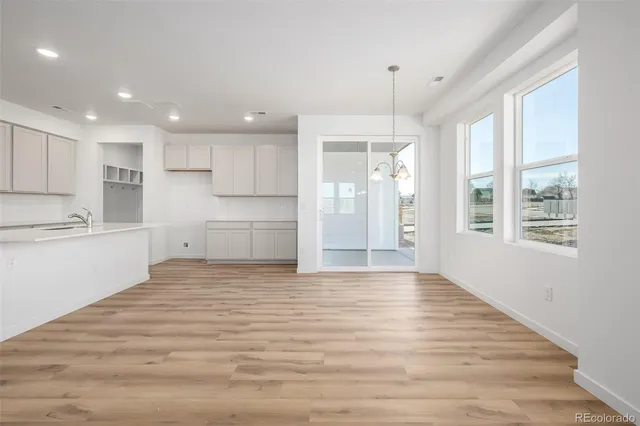 a view of an empty room with kitchen and window