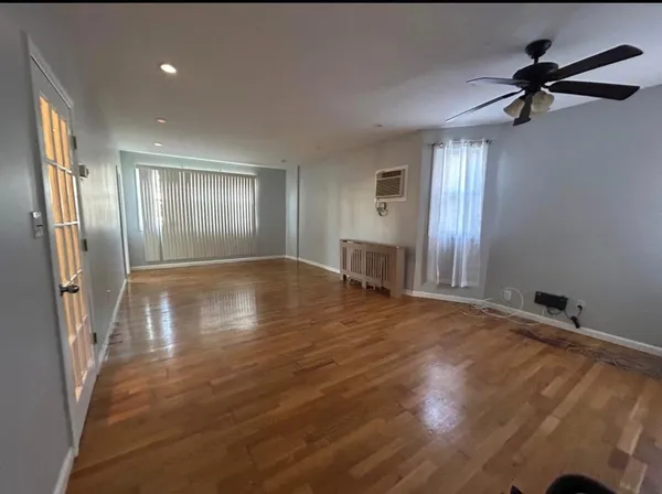 a view of empty room with wooden floor and window