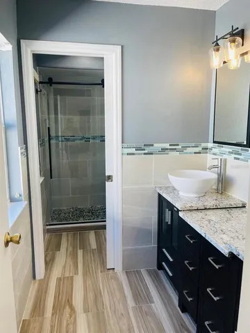 a bathroom with a granite countertop sink a mirror and shower