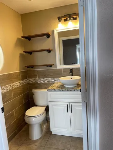 a bathroom with a granite countertop toilet sink and mirror