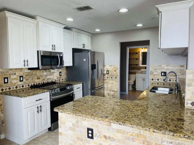 a kitchen with stainless steel appliances granite countertop a sink stove and refrigerator