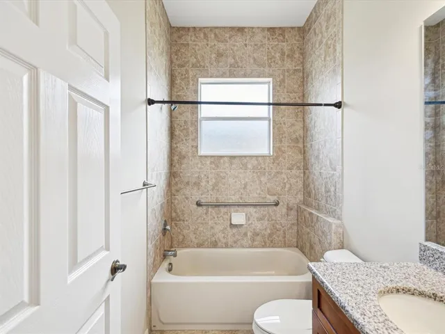 a bathroom with a granite countertop bathtub shower and toilet