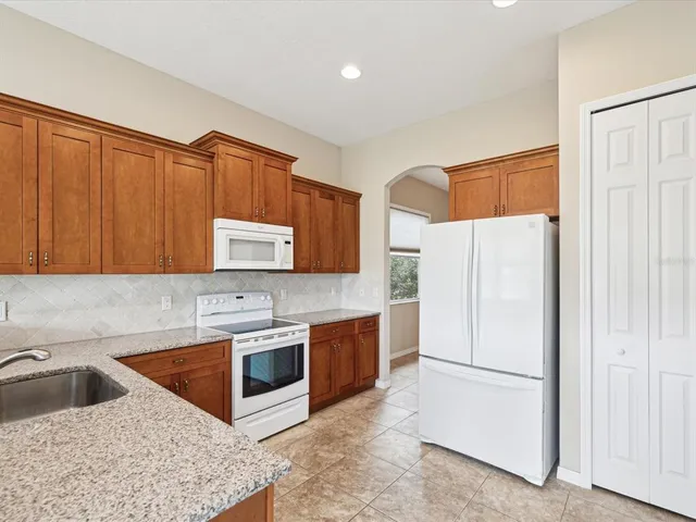 a kitchen with stainless steel appliances granite countertop a refrigerator a stove a sink and a microwave