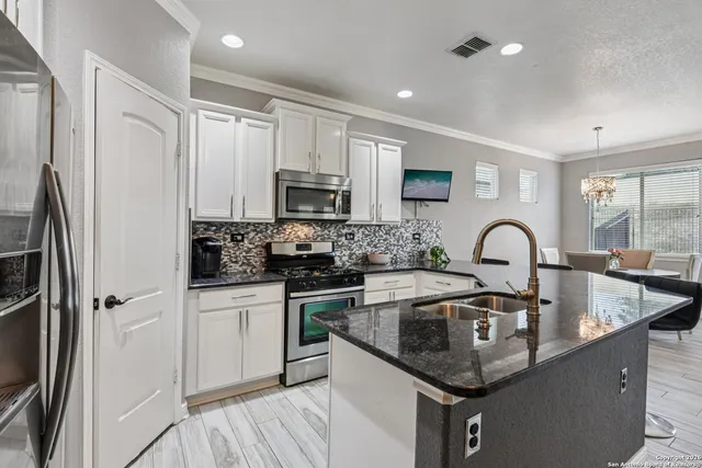 a kitchen with stainless steel appliances granite countertop a sink a stove and a refrigerator