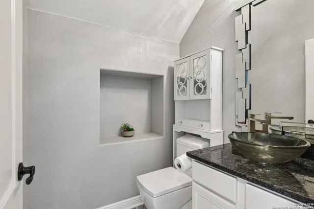 a bathroom with a granite countertop sink a toilet and a mirror