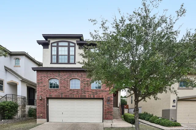 a front view of a house with a tree