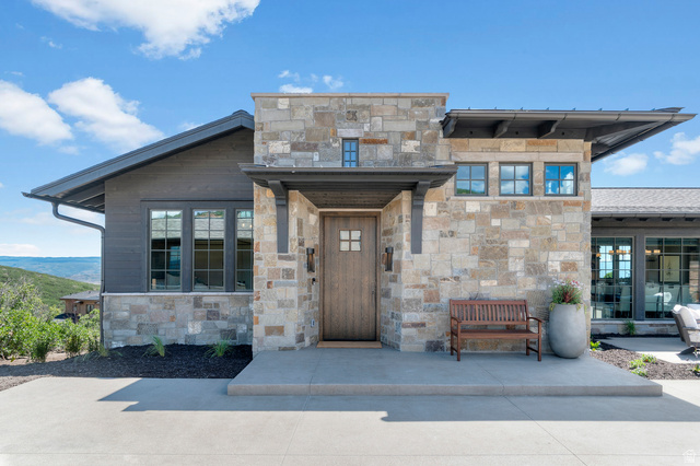 2192 East Outlaw Road Kamas, UT 84036 - Photo 65 of 80 Stone and wood-sided exterior with an angled roofline, a solid wood entry door, and dark-framed windows