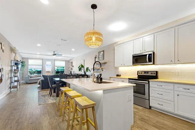 a kitchen with stainless steel appliances granite countertop a stove top oven a sink dishwasher and white cabinets with wooden floor