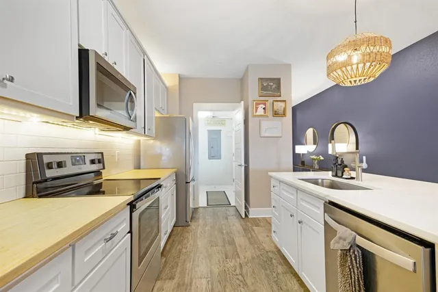 a large kitchen with stainless steel appliances granite countertop a stove a sink dishwasher a microwave oven with cabinets and wooden floor