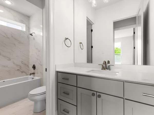 a bathroom with a granite countertop toilet a sink a mirror a bathtub and vanity