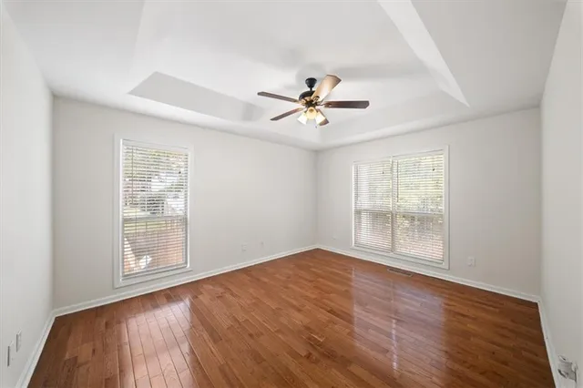 an empty room with windows and ceiling fan