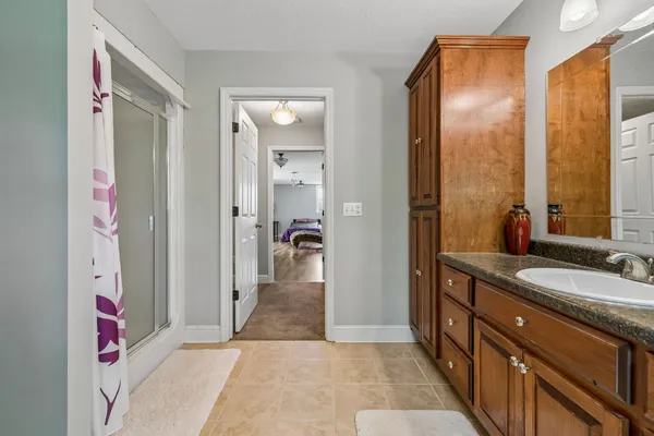 a bathroom with a granite countertop sink a mirror and a shower