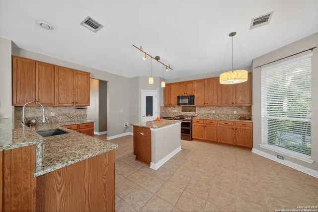 a large kitchen with kitchen island granite countertop a large counter top space a sink stainless steel appliances and cabinets