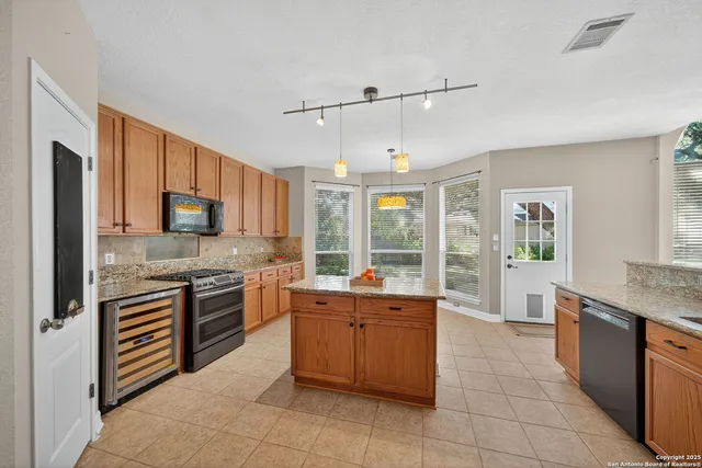 a large kitchen with stainless steel appliances granite countertop a stove sink and cabinets