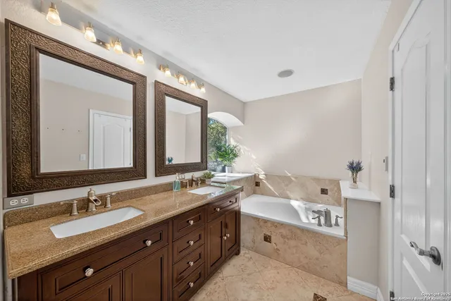 a bathroom with a tub double vanity sink and mirror