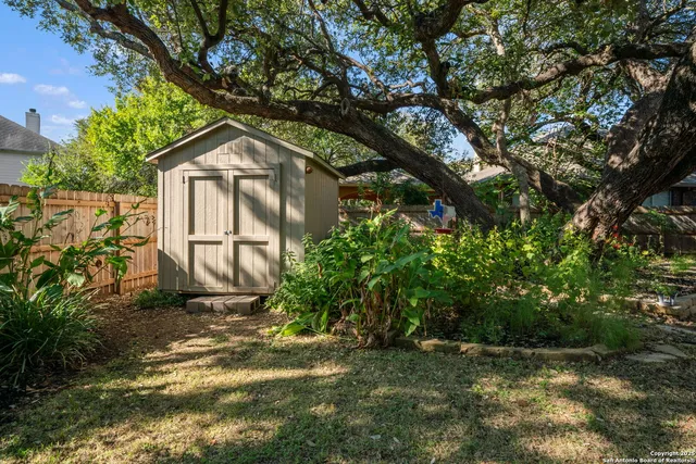 a backyard of a house with large trees and plants