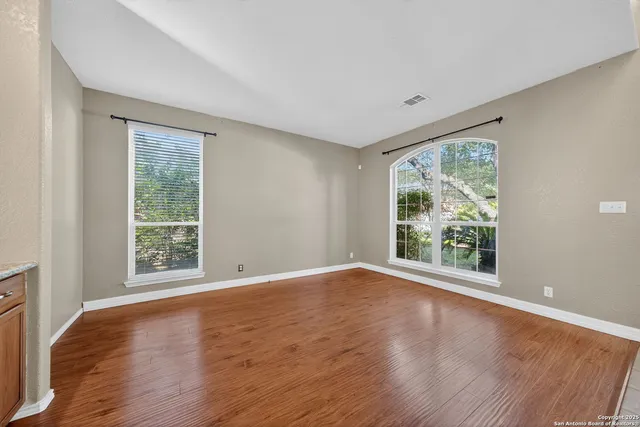 a view of an empty room with wooden floor and a window