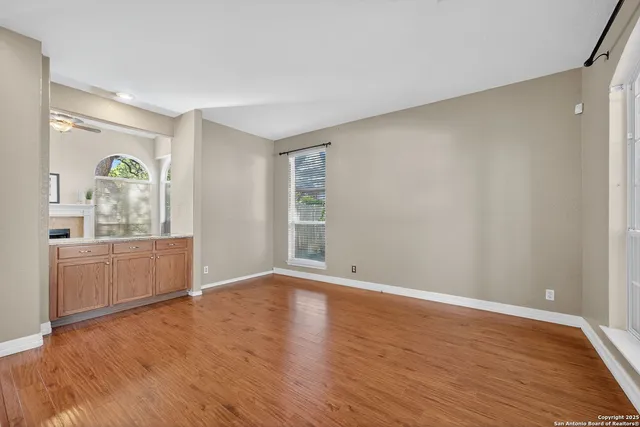 a view of an empty room with a window and wooden floor