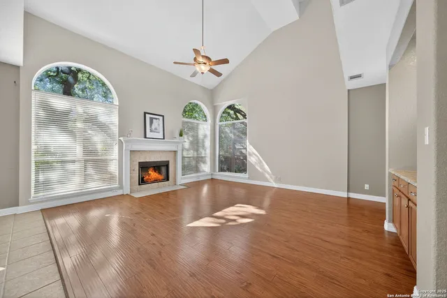 a view of an empty room with wooden floor fireplace and a window