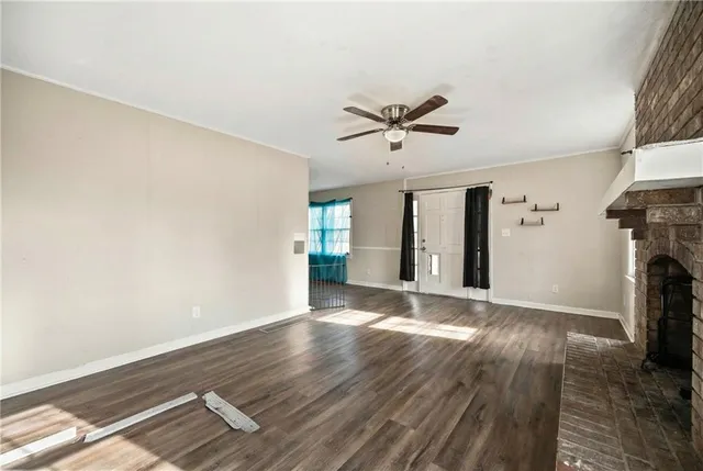 a view of an empty room with window and wooden floor