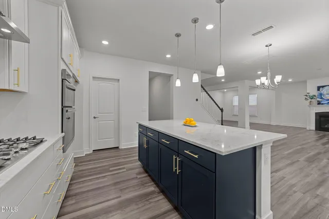 a kitchen with a stove a sink a center island and wooden floor