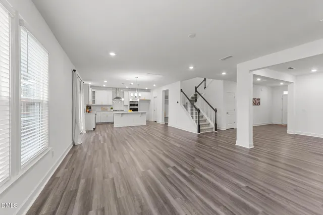 a view of a hallway with wooden floor and a kitchen