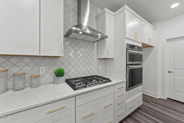 a kitchen with stainless steel appliances a white cabinets and a stove top oven