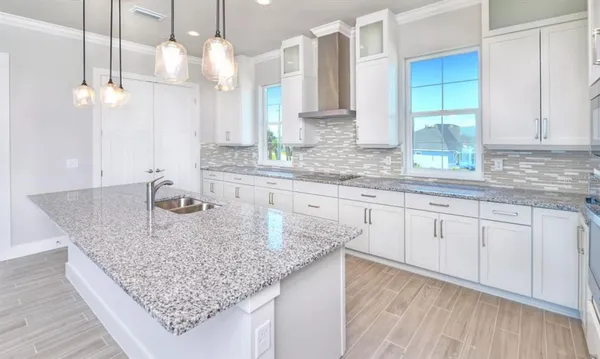 a kitchen with kitchen island granite countertop a sink cabinets and wooden floor