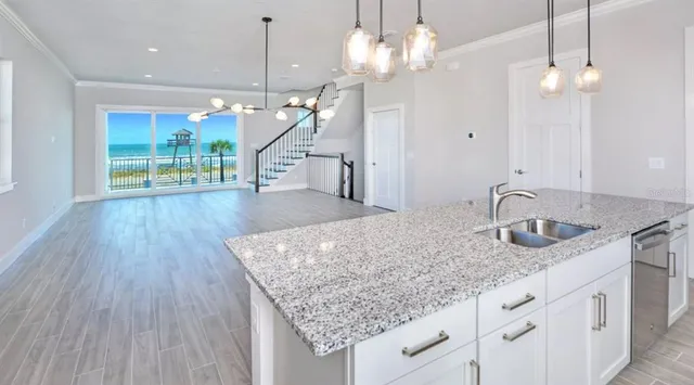 a kitchen with granite countertop a coffee maker a sink dishwasher and white cabinets with wooden floor
