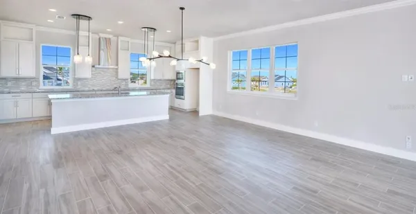 a large kitchen with stainless steel appliances kitchen island a large counter top space a sink wooden floor and a window