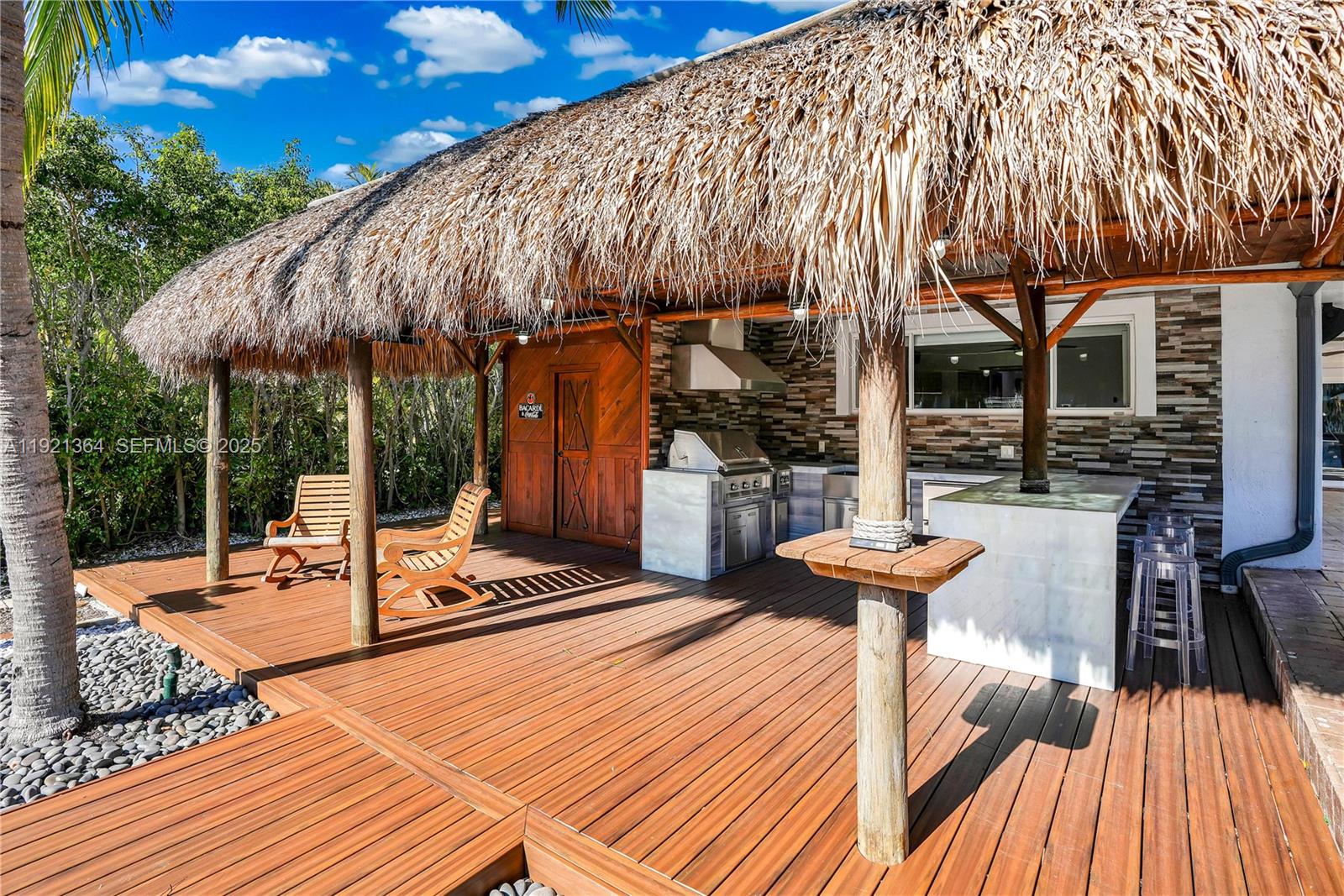 2130 Northeast 122nd Road North Miami, FL 33181 - Photo 25 of 86 a view of a patio with table and chairs under an umbrella with a barbeque