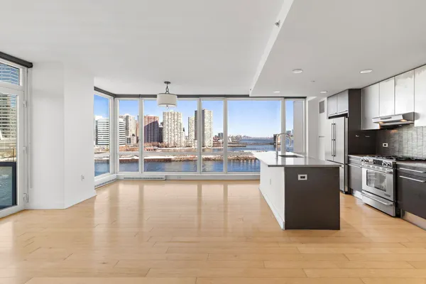 a large white kitchen with stainless steel appliances kitchen island granite countertop a large counter top cabinets and a couch
