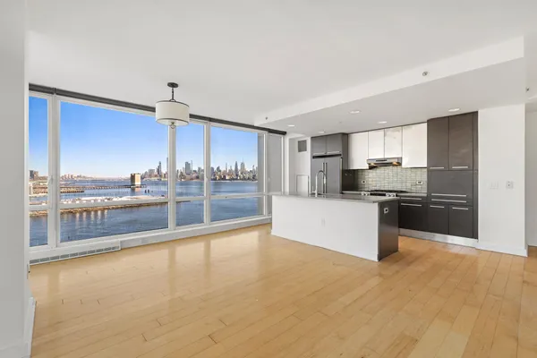 a large kitchen with a large counter top a sink stainless steel appliances and cabinets