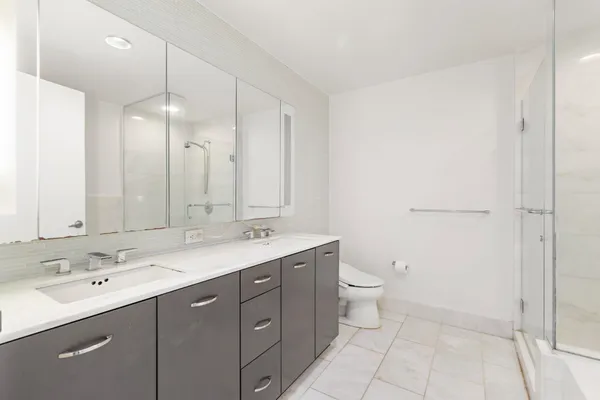 a spacious bathroom with a double vanity sink a toilet and a shower