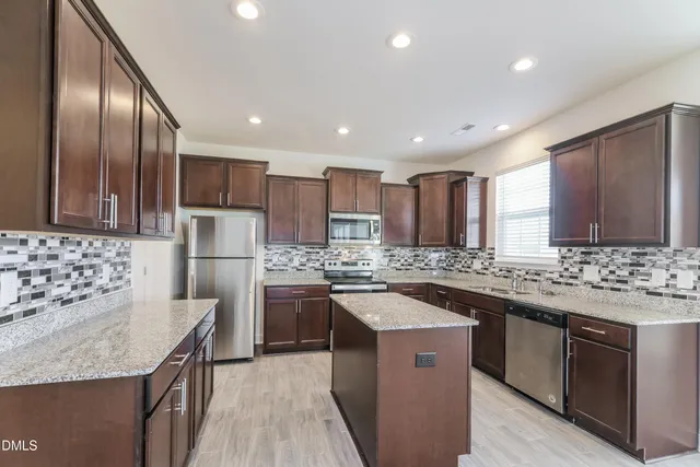 a kitchen with stainless steel appliances granite countertop a stove a sink a refrigerator and a oven
