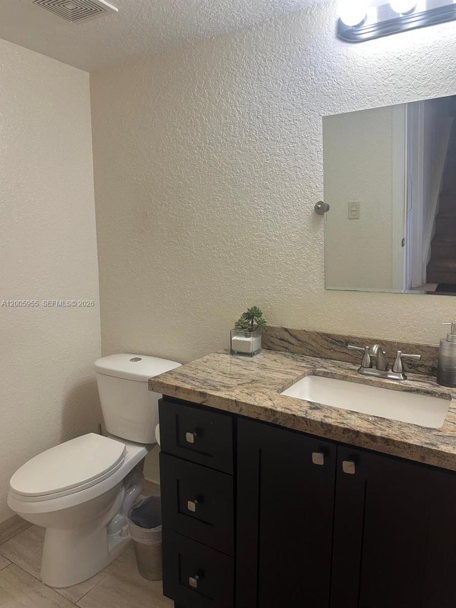 6920 West Sample Road, Unit 6920 Pompano Beach, FL 33063 - Photo 6 of 30 a bathroom with a granite countertop toilet sink and mirror