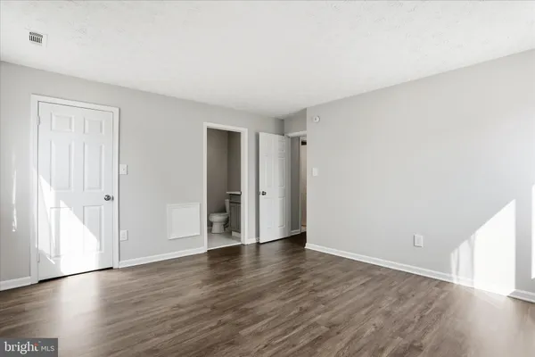 a view of an empty room with wooden floor and closet