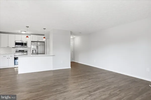 a view of kitchen with kitchen island wooden floor and stainless steel appliances