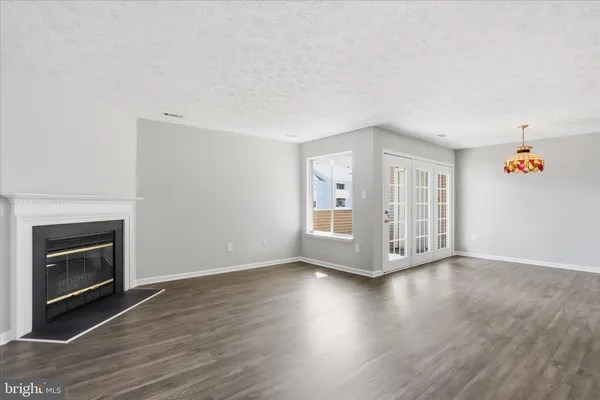 an empty room with wooden floor fireplace and windows
