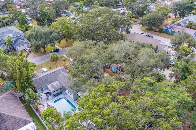 an aerial view of residential houses with outdoor space and trees all around