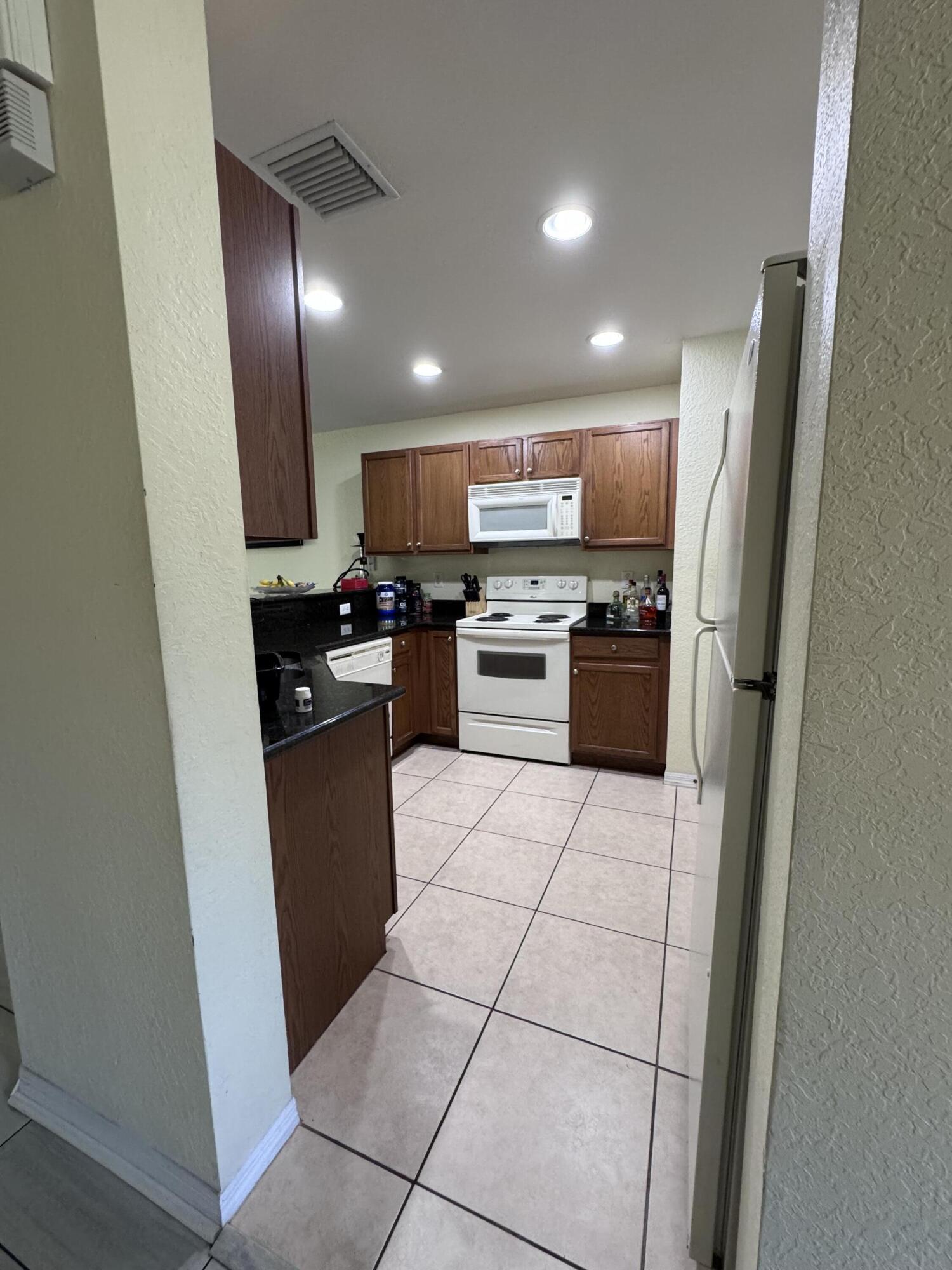 2755 Southeast Birmingham Drive, Unit 3 Stuart, FL 34994 - Photo 4 of 23 a kitchen with granite countertop a refrigerator a stove top oven and sink