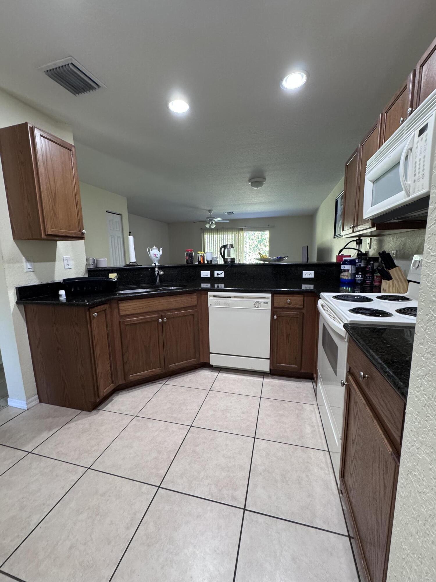 2755 Southeast Birmingham Drive, Unit 3 Stuart, FL 34994 - Photo 6 of 23 a large kitchen with granite countertop a stove top oven a sink dishwasher and a refrigerator