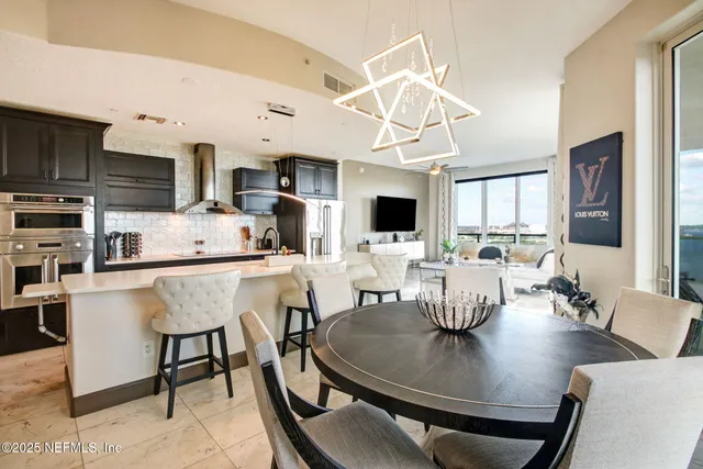 a living room with stainless steel appliances kitchen island granite countertop a dining table chairs and a kitchen view