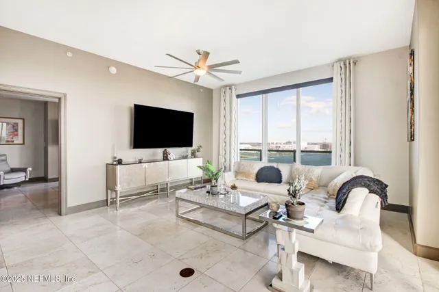 a living room with furniture a flat screen tv and a large window