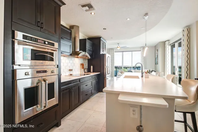 a large kitchen with stainless steel appliances large white cabinets and a stove top oven