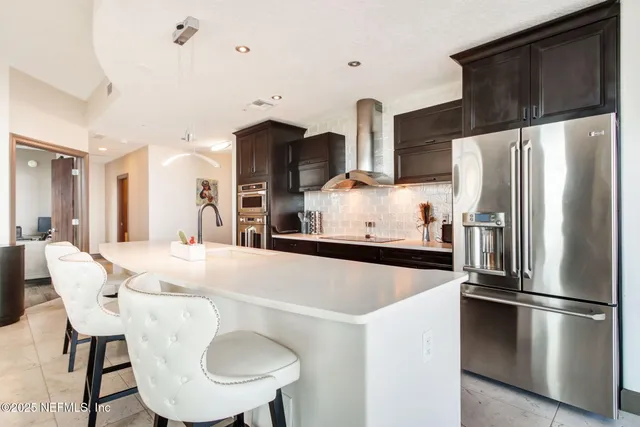 a kitchen with stainless steel appliances a refrigerator a sink a stove a dining table and chairs