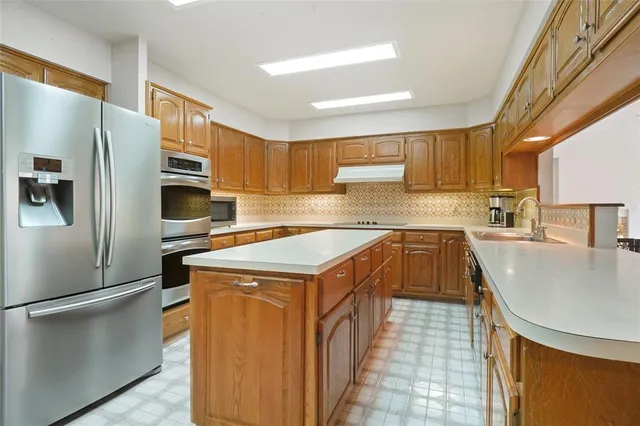 a kitchen that has a sink a refrigerator and a stove top oven